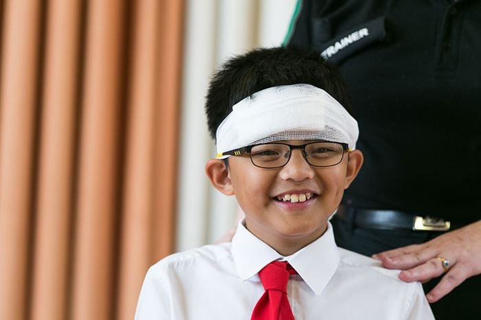 School child smiling with bandage around head