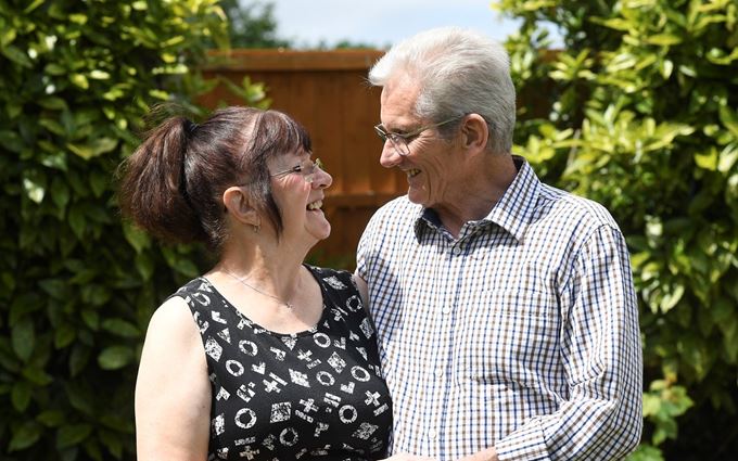 Gwen and John standing in a garden holding hands.