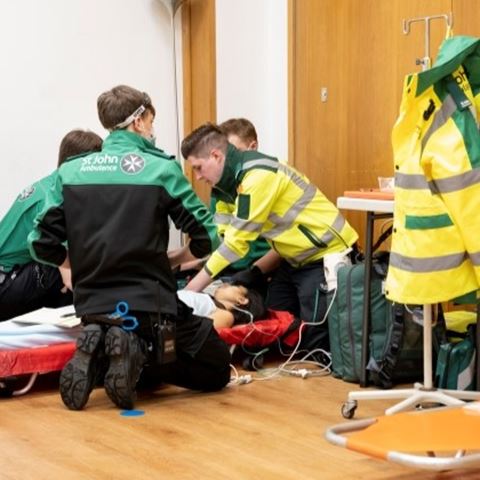 Four volunteers treating a casualty lying down on a stretcher.