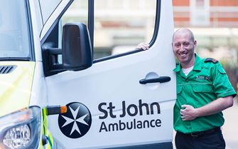 St John Ambulance driver standing next to the open door of an ambulance