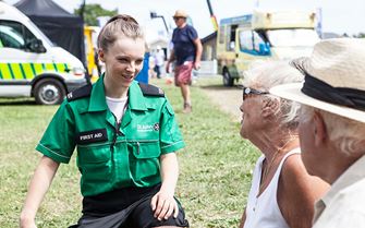 First aider attending elderly couple at outdoor event