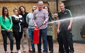 Man, practices using a fire extinguisher during a fire marshal training course.