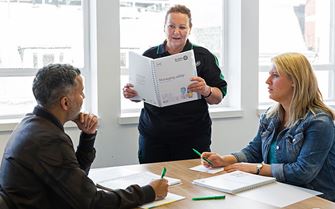 The trainer shows participants the IOSH Managing Safety workbook during a training course. 