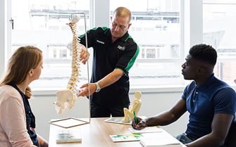 St John Ambulance trainer teaching a class about spinal anatomy..