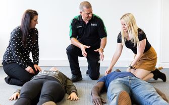First aid course participants learning how to put someone in the recovery position