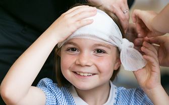 School child smiling with bandage around head.