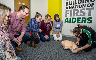 Trainer teaches CPR by lifting a training mannequin chin to check if the airway is open in a first aid training course.