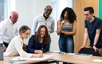 Class participants watching another class participant write on a mental health first aid training course.