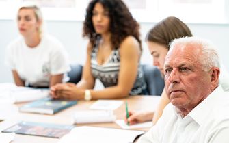 Class participants sat around a table with study materials on a mental health first aid training course. 