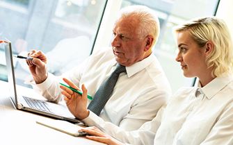  Two adults sat down looking at a laptop managers’ resilience course. 