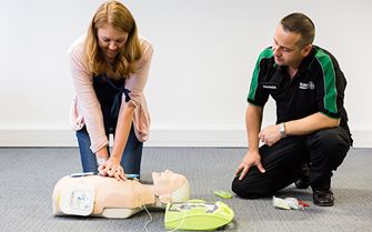 St John Ambulance course participant practicing CPR on a training mannequin.