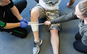 St John Ambulance trainer demonstrates how to apply a bandage to a leg wound during a basic sports first aid course. 
