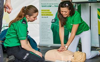 St John Ambulance volunteer teaching a young woman CPR